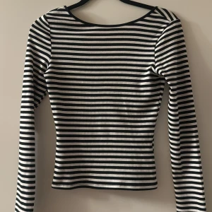 Randig långärmad topp från Gina Tricot - Säljer en svartvit randig långärmad topp från Gina Tricot. Toppen har rundad halsringning och är tillverkad i ribbad bomull som sitter snyggt på kroppen. Perfekt att styla med jeans eller kjol för en cool och enkel look.