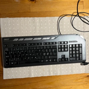 Acer SK-9625 Tangentbord - Acer SK-9625 är ett robust, trådbundet tangentbord med numerisk del och multimedietangenter. Svensk layout, USB-anslutning. Tangenterna visar visst slitage och smuts, men allt verkar fungera. Perfekt för kontor eller hemmabruk.