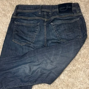 Blå jeans från Jacob Cohen - Säljer ett par klassiska blå jeans från Jacob Cohen. Jeansen har en skön rak passform och sitter sjukt skönt. Perfekta för dig som gillar en avslappnad stil. Skulle säga att de passar dig som är runt 170 perfekt! Priset kan även diskuteras!