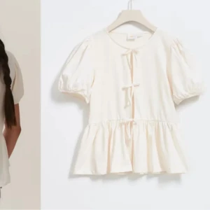 Vit blus med knyt och puffärm - Supersöt vit blus med kort puffärm och två knyt framtill. Blusen har en volang nedtill som ger en luftig och romantisk känsla. Perfekt för dig som gillar en feminin och trendig stil. Köpte den för 229. Helt oanvänd🩷