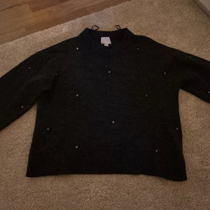 Svart stickad tröja med pärlor H&M XS - Mysig svart stickad tröja från H&M i storlek XS. Tröjan har långa ärmar och är dekorerad med små pärlor över hela framsidan för en extra touch. Perfekt för dig som gillar en enkel men ändå glittrig look.