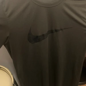 Svart Nike Dri-FIT t-shirt M - Snygg svart t-shirt från Nike med klassisk Swoosh-logga på bröstet. Tillverkad i Dri-FIT-material som andas och håller dig torr. Perfekt för träning eller chill, med normal passform och korta ärmar.
