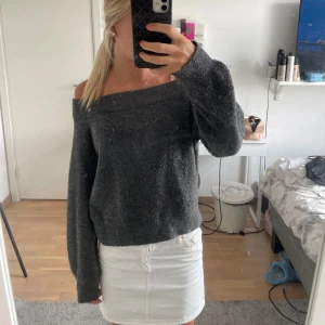Mörkgrå offshoulder stickad tröja - Mysig mörkgrå stickad tröja med offshoulder-modell och långa ärmar. Tröjan har en loose passform och är perfekt för dig som gillar en avslappnad men ändå trendig stil. Passar snyggt till både jeans och kjol.