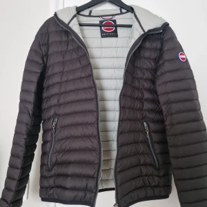 Svart pufferjacka från Colmar - Säljer en svart pufferjacka från Colmar med huva och två fickor med dragkedja. Jackan har ett quiltat, horisontellt mönster och Colmar-logga på ärmen. Perfekt för kyliga dagar och har en snygg, sportig look. Inga defekter, fåtal gånger använd. Priset är inte skrivet i sten och kan diskuteras vid snabb affär. Undrar ni något är det bara att skriva :) 