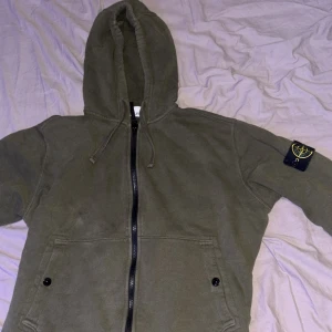 Mörkgrön Stone Island zip - En riktigt stilren och snygg tröja perfekt för alla tillfällen. Den sitter bra mot kroppen och ser sjukt bra ut. Priset är hugget i sten 