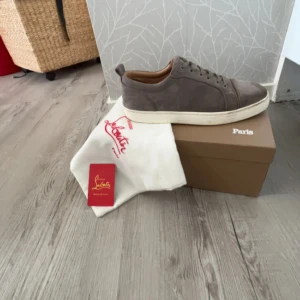Grå mocka sneakers från Louboutin - Säljer nu mina gråa louboutins då jag har köpt nya skor. En mycket snygg sko som passar till iprincip allt. Vid köp ingår bara dustbagen då jag har slarvat bort orginal boxen. Skorna är mycket använda och har hyfsat bra skick. Mockan är okej fortfarande men det är den röda sulan som är lite smutsig men går att rädda om man försöker. Därav det låga priset för denna sko! Storleken är 41 men jag tycker att dom sitter som 42. Skriv vid funderingar eller intresse!