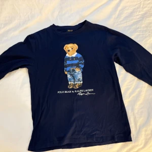 Mörkblå långärmad tröja Polo Ralph Lauren - Säljer en mörkblå långärmad tröja från Polo Ralph Lauren med ikoniska Polo Bear-trycket framtill.  Aldrig använd, skickas samma dag och mer bilder kan ordnas Mvh! 