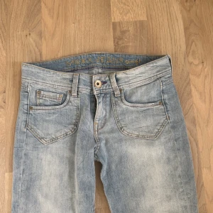 Ljusblå jeans från MEXX - Ljusblå jeans från MEXX med straight fit, klassiska fem fickor och slitna, fransiga benslut. Snygga detaljer på bakfickorna och ett broderat märke bak. Jeansen har en avslappnad vibe och är tillverkade i denim. lågmidjade snygga jeans storlek S:36💗 midjemått 37cm innerbenslängd 75cm fotvidd 18cm pris kan diskuteras vid snabb affär💞
