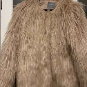 Beige pälsjacka från Lindex - Säljer en fluffig och trendig beige pälsjacka från Lindex i storlek S. Jackan har lång lugg och ger en riktigt cool statement-look. Perfekt för dig som vill sticka ut och hålla dig varm med stil. Fodrad insida för extra komfort. Färgen är rosa / Champagne 
