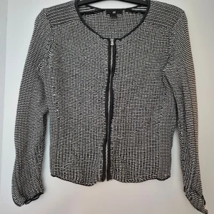 Svartvit cardigan jacka från H&M - Snygg svartvit cardigan jacka från H&M i stickat material. Jackan har ett randigt mönster, rund halsringning och dragkedja framtill samt på ärmsluten. Perfekt för dig som gillar en stilren och trendig look.