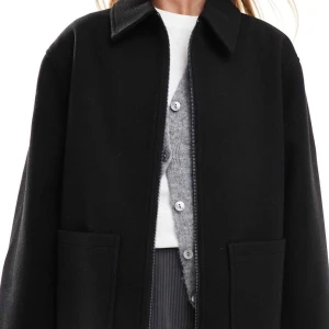 Svart ulljacka med dragkedja - Stilren svart jacka i ull med rak passform, klassisk krage och stora fickor framtill. Jackan har dragkedja och är helfärgad utan mönster, perfekt för dig som gillar minimalistisk stil.