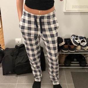 Rutig mjukisbyxa från Kappahl S - Rutig mjukisbyxa från Kappahl i vitt och mörkblått med snörning i midjan. Byxorna har avslappnad passform och är tillverkade i mjukt bomullstyg, perfekta för chill dagar hemma.