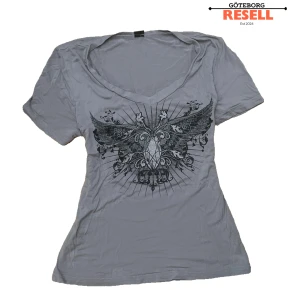 Grå t-shirt med v-ringad hals - Cool tshirt med edgy vibe. Väl använd. affliction-liknande print. Skick 6/10, passar S, M som tight fit