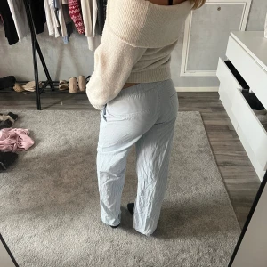 Ljusblå randiga linnebyxor - Säljer ett par ljusblå kostym/hemma byxor med smala vita ränder. Byxorna har en relaxed passform med raka ben och low waist. Perfekta för en chill och stilren look, passar dig som gillar bekväma och luftiga plagg. Ny pris 600. Även en fleck typ precis i början av fickan vilket inte syns typ och sen en liten på knät som inte heller syns eller man tänker på.