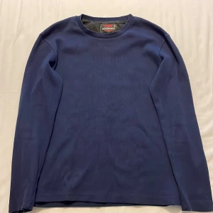 Marinblå långärmad tröja Reference - Snygg marinblå långärmad tröja från Reference Collection i storlek S och passar M. Tröjan har en enkel och clean design med rund hals och är tillverkad i ett mjukt syntetmaterial. Perfekt för dig som gillar stilrena och bekväma plagg. Priset kan diskuteras 