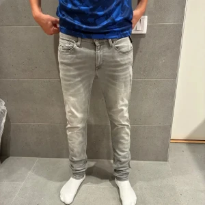 Replay ljusgrå jeans - Säljer ett par ljusgrå  jeans från Replay med klassisk femficksdesign och diskret logga på bakfickan. Jeansen har smal passform och är tillverkade i stretchigt jeanstyg för extra komfort. Perfekta för dig som gillar en modern och stilren look.