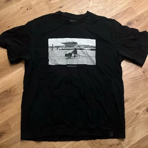 Vintage Svart T-Shirt - Svart t-shirt från Related med en stor svartvit print på bröstet som är en person på cykel och texten 'You only live once'.