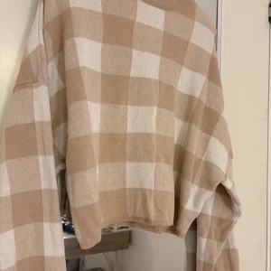 Beige och vit rutig stickad tröja Gina Tricot - Supermysig stickad tröja från Gina Tricot i storlek S. Tröjan har ett rutigt mönster i beige och vitt, med lång ärm och avslappnad passform. Perfekt för att ge din outfit en chill vibe och funkar lika bra till jeans som till kjol.