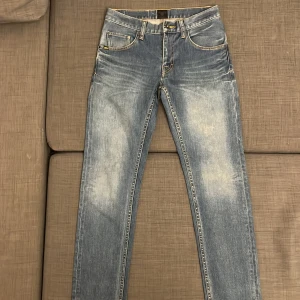 Tiger of Sweden ljusblå jeans - Snygga ljusblå jeans från Tiger of Sweden med klassisk femficksdesign och kontrastsömmar. Jeansen har en straight passform och är tillverkade i bomull med lite stretch för extra komfort. Faded effekt framtill och bak ger en cool vibe.