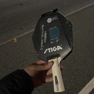 Stiga Cybershape Hobby - Stiga Cybershape Hobby är ett unikt pingisracket med större träffyta och modern design. Racket är nytt, fortfarande i originalförpackning och plast. Perfekt för hobbyspelare som vill ha kontroll och fart. Inga synliga defekter eller slitage.