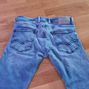 Ljusblå Reaplay Jeans - Säljer ett par snygga ljusblå jeans från Replay med klassisk femficksdesign och raka ben. Jeansen har lite diskreta slitningar som inte syns om man inte kollar noggrant. Den har replays coola detaljer på bakfickorna samt Replay-logga på linningen. Perfekt för dig som gillar en avslappnad och stilren look. Jeansen är mjuka och har bra stretching som ger dig en skönare upplevelse. Jeansen kostar 1300kr i nypris. Dem har bara använts i två månader. 