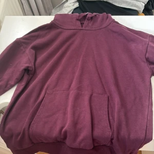 Vinröd hoodie från Gina Tricot - Mysig vinröd hoodie från Gina Tricot med huva och stor magficka. Tröjan har långa ärmar och ribbade muddar. Perfekt för chill dagar och enkel att matcha med jeans eller leggings.