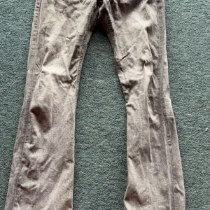 Grå bootcut jeans från Gina Tricot - Snygga grå jeans från Gina Tricot i bootcut-modell med klassiska silverfärgade knappar framtill. Jeansen har en rak passform över låren och blir vidare nedtill, vilket ger en cool siluett. Materialet är slitstarkt jeans och färgen är en neutral gråton.