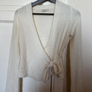 En jättesöt vit kofta med en rosett på sidan - Jättesöt kofta från Gina Tricot som passar till ett par jeans eller en kjol💕har använt typ 2ggr
