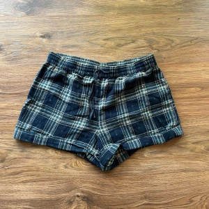 Pyjamasshorts - Snygga blå-rutiga shorts från Day Dreams Duvet Days med snörning i midjan. De har en loose passform och är gjorda i mjuk bomull, perfekta för chill dagar. Rutmönstret går i blått och vitt med inslag av beige. Elastisk midja för extra komfort.