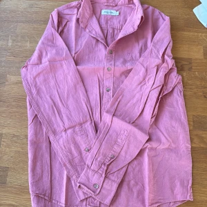 Rosa linneskjorta från Dressmann L - Säljer en rosa skjorta från Dressmann i linnemix. Skjortan har klassisk krage, knäppning framtill och en bröstficka. Perfekt för dig som gillar en avslappnad men ändå stilren look. Passar M-L