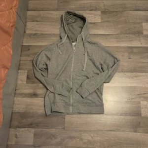  Lacoste tracksuit  - Snygga grå mjukisbyxor från Lacoste med klassisk krokodillogga på benet. Byxorna har resår och snörning i midjan samt muddar vid bensluten. Perfekta för chill eller träning, tillverkade i mjuk bomullsblandning för maximal komfort. Top ingår