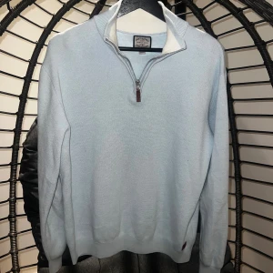 Ljusblå half zip tröja Next Supply - Snygg ljusblå tröja från Next Supply med half zip-dragkedja och hög krage. Tröjan är långärmad och har en stilren, enkel design som passar perfekt till jeans eller chinos. Mjuk och skön känsla, perfekt för lager-på-lager.