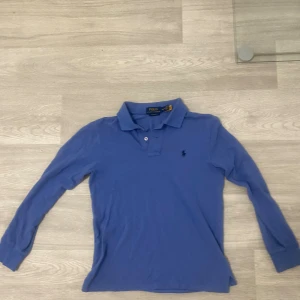Långärmad piké tröja från polo Ralph lauren  - Säljer min blå långärmad piké tröja från polo Ralph lauren som jag har köpt för 1000kr mitt prisa 350kr.  Den är storlek xs/xxs passar för dig som är 150-160. Den är i bra skick inga defekter. Pris går att diskuteras såklart. Skriv till mig vid minsta lilla fundering.