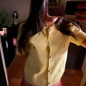 Gul kortärmad kofta från Zara - Superfin ljusgul kofta från Zara med korta ärmar och snygga guldiga knappar framtill. Tröjan har två fickor på bröstet och ribbad kant vid halsen. Perfekt för vår och sommar när du vill ha en färgklick i garderoben!