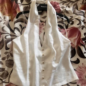 Vit halter linnetopp med knappar från Zara - Supersnygg vit halter linnetopp från Zara med djup v-ringning och halterneck med dragkedja i sidan💕(säljs också på Vinted, användarnamn: annsen.01)