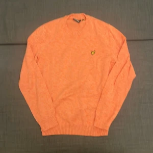 Orange stickad tröja Lyle & Scott - Säljer en snygg orange stickad tröja från Lyle & Scott i storlek S. Tröjan har lång ärm, rund hals och den klassiska gula fågel-loggan broderad på bröstet. Materialet är mjukt och skönt, perfekt för dig som gillar stilrena och färgglada plagg.