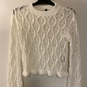 Vit stickad tröja med hålmönster - Säljer en vit stickad tröja med snyggt hålmönster och vågiga detaljer. Tröjan har rund halsringning, långa ärmar och ribbade muddar. Helt oanvänd💕