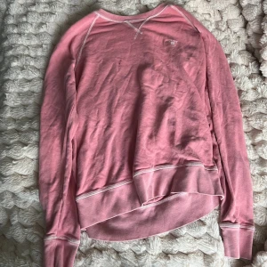 Rosa sweatshirt från GANT - Säljer en rosa sweatshirt från GANT med vit broderad logga på bröstet. Tröjan har långärmade raglanärmar, vit kontrastsöm och rund hals. Mjuk bomullskvalitet, tror storleken är S lappen är bortklippt.