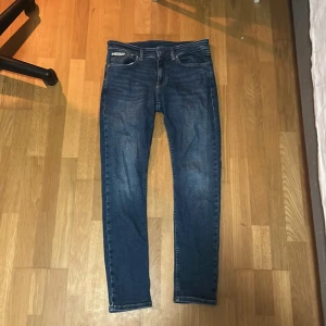 Blå skinny jeans från Calvin Klein W32 L32 - Snygga blå skinny jeans från Calvin Klein med klassisk femficksdesign och läderpatch bak i midjan. Endast använt ett fåtal gånger.