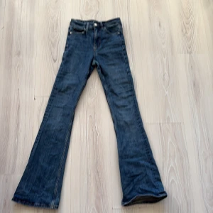 Blå bootcut jeans från Gina Tricot - Snygga blå bootcut jeans från Gina Tricot, modell Perfect Jeans. Klassisk femficksdesign, normal passform och utsvängda ben. Jeansen är i ett mjukt denimtyg och har en tidlös blå tvätt som passar till allt.