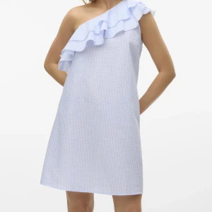 Blåvit randig one shoulder klänning - Superfin kort klänning i blåvitt randigt tyg med volangdetalj över axeln. One shoulder-modell som ger en trendig look, perfekt för varma dagar. Lätt och luftig känsla, passar dig som gillar en avslappnad men ändå chic stil.