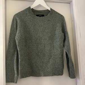 Grå stickad tröja från Vero Moda - Mysig grå stickad tröja från Vero Moda i storlek XS. Tröjan har en klassisk rund halsringning och långa ärmar. Perfekt för kyliga dagar och enkel att matcha med jeans eller kjol.