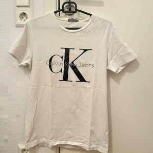 Vit t-shirt från Calvin Klein Jeans XS - Vit t-shirt från Calvin Klein Jeans med stor svart CK-logga framtill. Tröjan är i bra skick. Strl XS