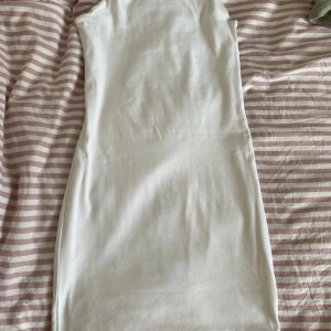 Vit ärmlös kortklänning - En enkel och stilren vit kortklänning i ärmlös modell. Klänningen har en rak passform och är tillverkad i mjukt bomullstyg, perfekt för varma dagar. Passar dig som gillar minimalistisk och clean stil.