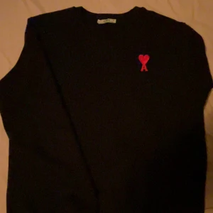 Svart tröja från Ami Paris med rött hjärta - Svart tröja från Ami Paris med klassisk passform och rund hals. På bröstet finns Ami:s ikoniska röda hjärta med bokstaven A broderat. Perfekt basic med en snygg detalj som sticker ut. Pris kan diskuteras!! 