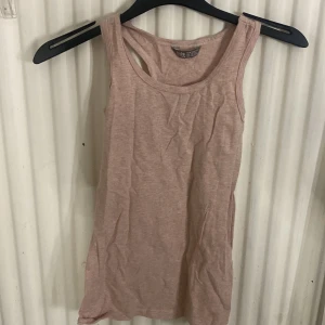 Ljusrosa linnetopp  - En enkel och stilren ljusrosa linnetopp i.Toppen är ärmlös med klassisk rund halsringning och rak passform, perfekt för varma dagar eller som lager under en skjorta.