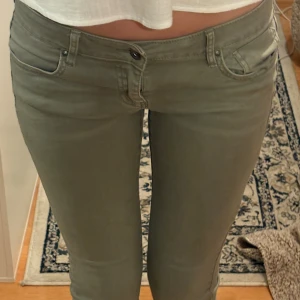 Olivgröna jeans från edc, stl 36 - Säljer ett par olivgröna jeans från edc i storlek 36. Byxorna har låg midja, klassisk femficksdesign och är tillverkade i ett stretchigt bomullsmaterial för en tight passform. Perfekta för dig som gillar en smal siluett och stilren look.