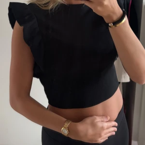 Svart topp med volang från Zara - Svart ribbad topp från Zara med volangdetaljer på axlarna. Knappt använd!