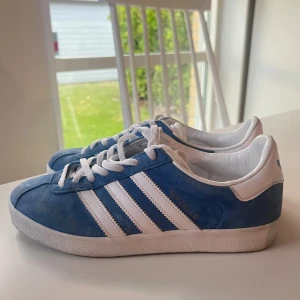 Adidas Gazelle blå - Säljer ett par Adidas Gazelle sneakers i blå mocka med vita detaljer och klassiska tre ränder på sidorna. Utan defekter och använda 2 ggr 💞💞