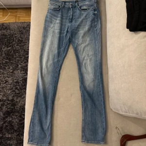 Blå jeans från BOSS med raka ben storlek W31L32 - Snygga ljusblå jeans från BOSS med klassisk femficksdesign och raka ben. Jeansen har subtila slitningar och kontrastsömmar, samt BOSS-lapp bak i midjan. Passar dig som gillar en clean och tidlös look. Dragkedja och knapp framtill.